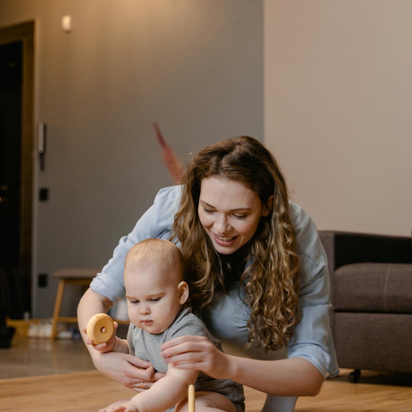 A mother and baby enjoying playtime with wooden toys at home, emphasizing warmth and care.